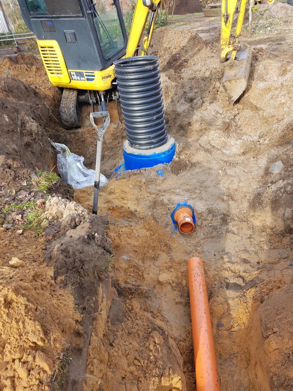 Montaż plastikowej studni drenarskiej z rurą karbowaną w wykopie Studnie