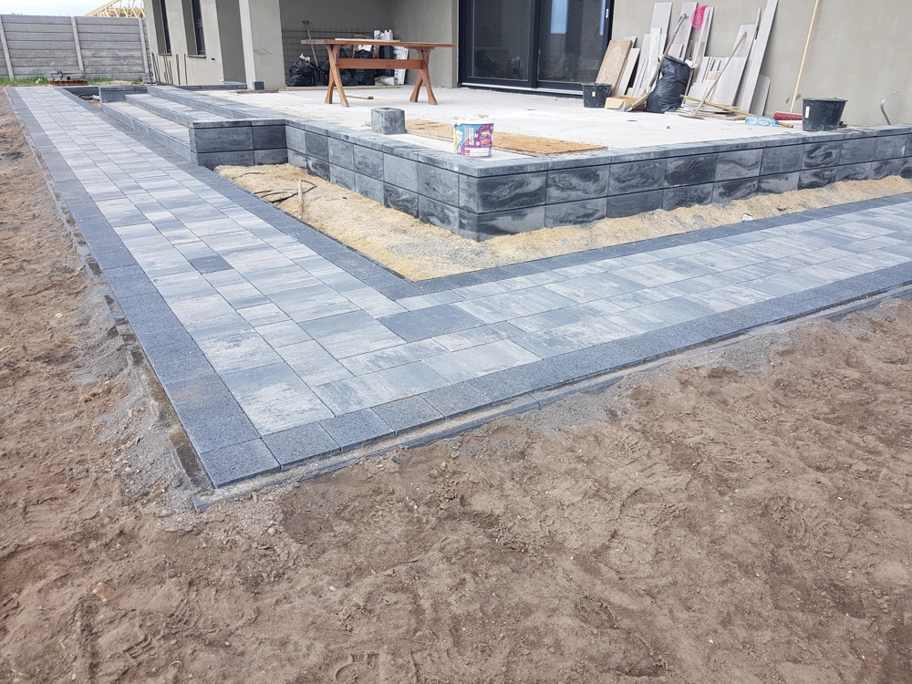 Opaska wokół domu z kostki wykonana na wyrównanym podłożu przy tarasie