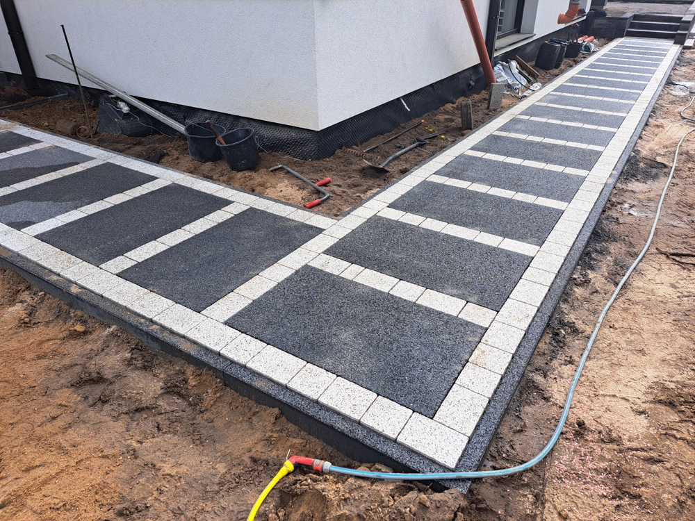 Opaska wokół domu z kostki brukowej w czarno-białym wzorze