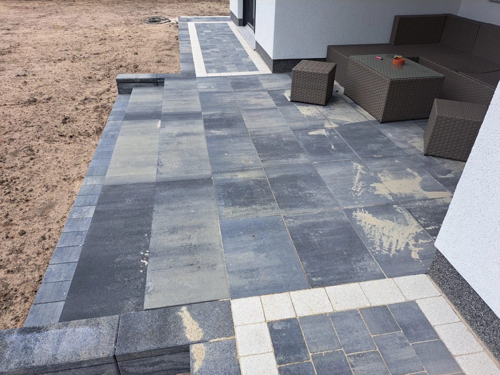 Układanie płyt tarasowych betonowych na tarasie przy budynku z meblami ogrodowymi