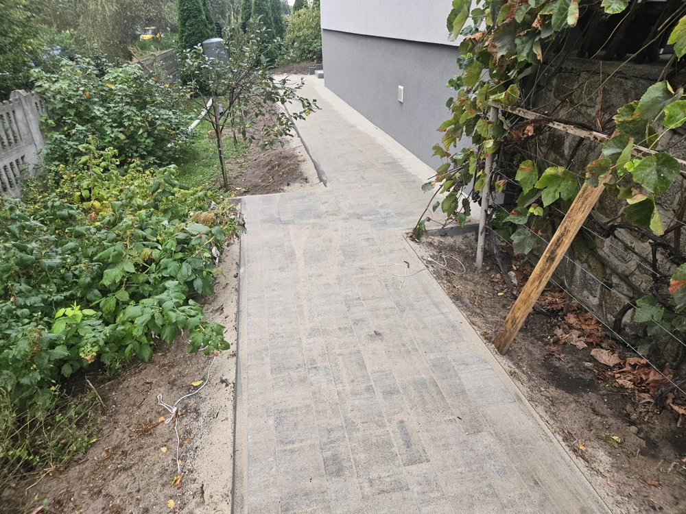 Opaska wokół domu z kostki przy ścianie budynku na przygotowanym podłożu