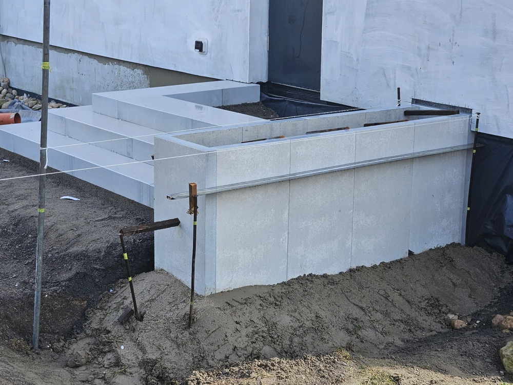 Schody betonowe z prefabrykowanych elementów na przygotowanym podłożu przy wejściu do budynku