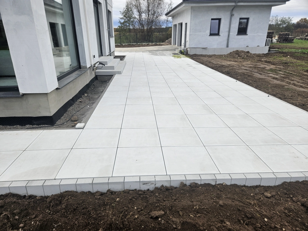 Układanie płyt tarasowych betonowych przy elewacji budynku