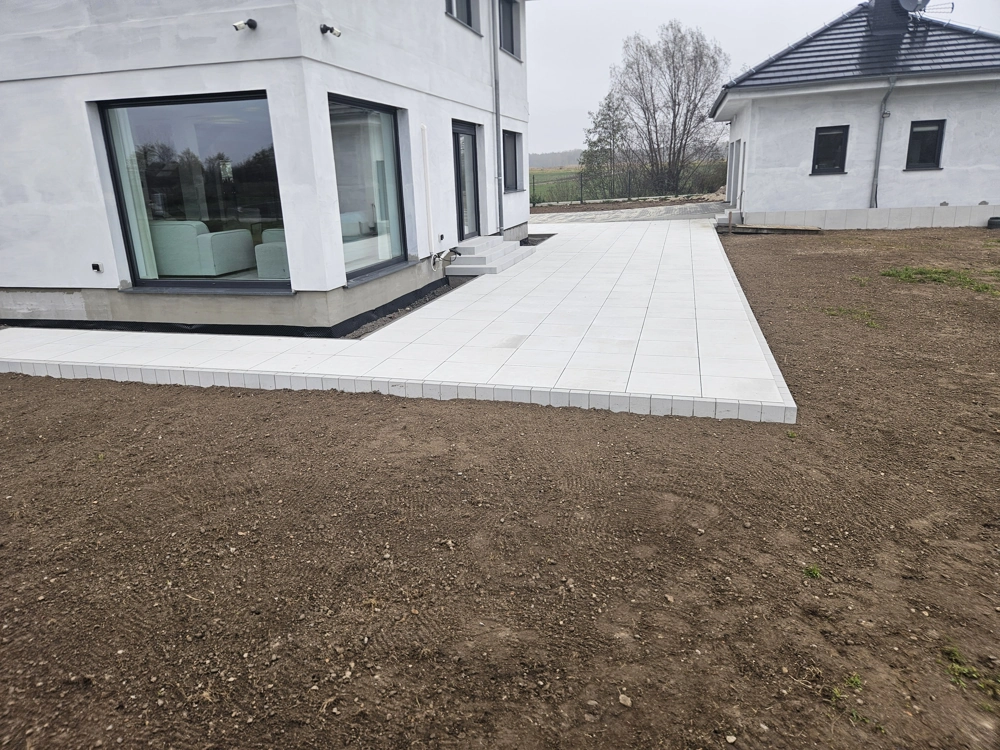 Płyty tarasowe betonowe tworzące nową opaskę wokół domu na wyrównanym terenie