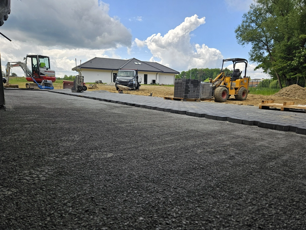 Układanie kostki brukowej z użyciem ładowarki kołowej na wyrównanym terenie