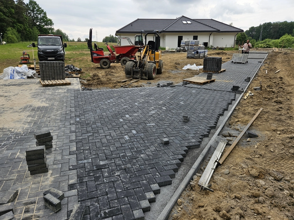 Układanie kostki brukowej na podjeździe z użyciem ładowarki kołowej i wozidła budowlanego
