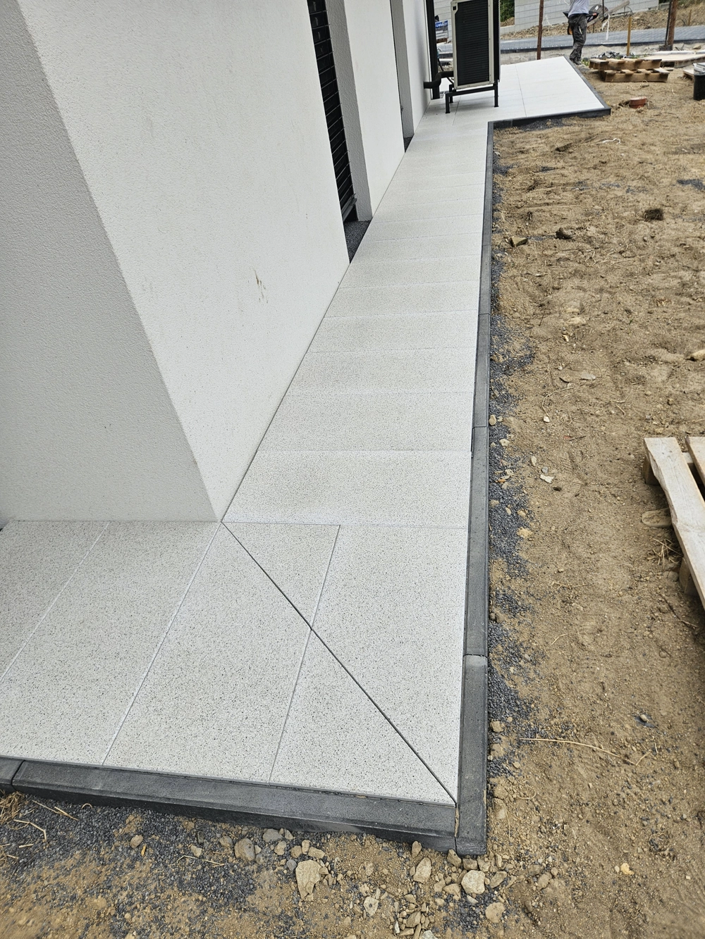 Opaska wokół domu z kostki betonowej na wypoziomowanym podłożu przy narożniku budynku