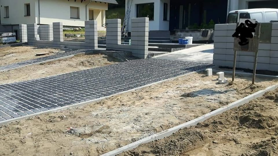 Układanie kostki brukowej na przygotowanym podłożu pod podjazd przed budynkiem mieszkalnym