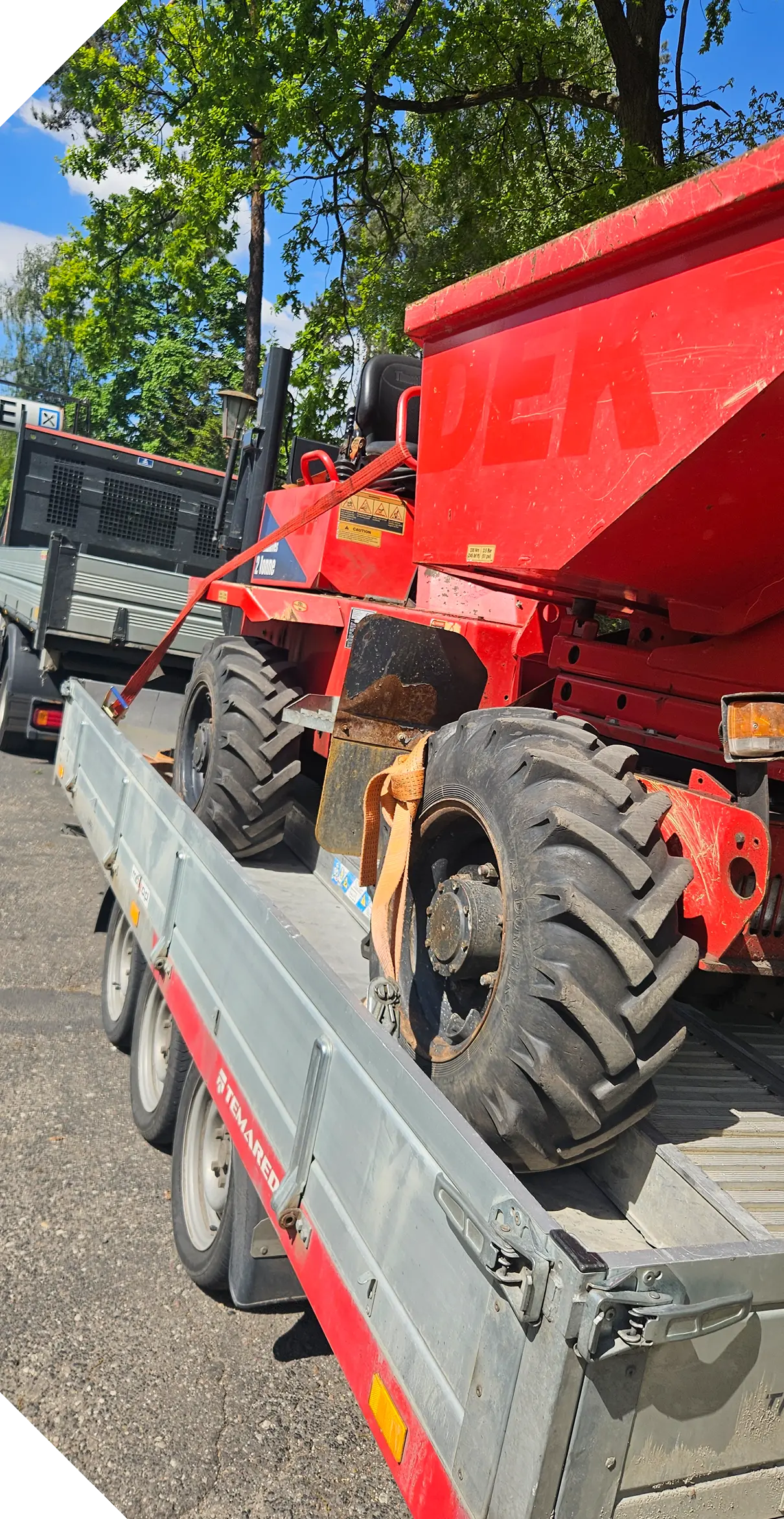 Czerwone wozidło budowlane załadowane na przyczepę do transportu na plac budowy