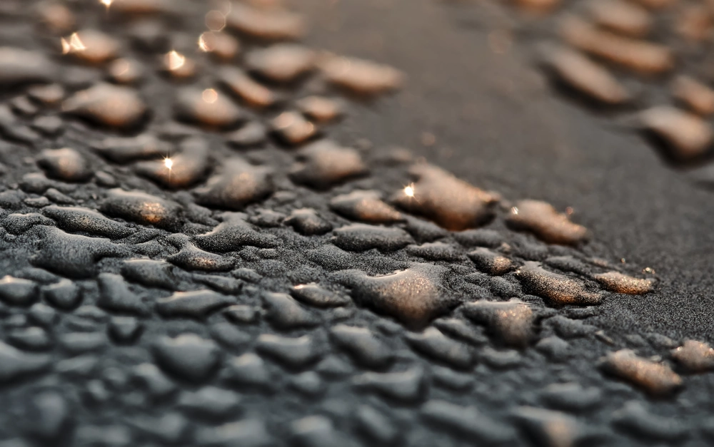 Impregnacja kostki brukowej – kropelki wody na ciemnej, hydrofobowej powierzchni